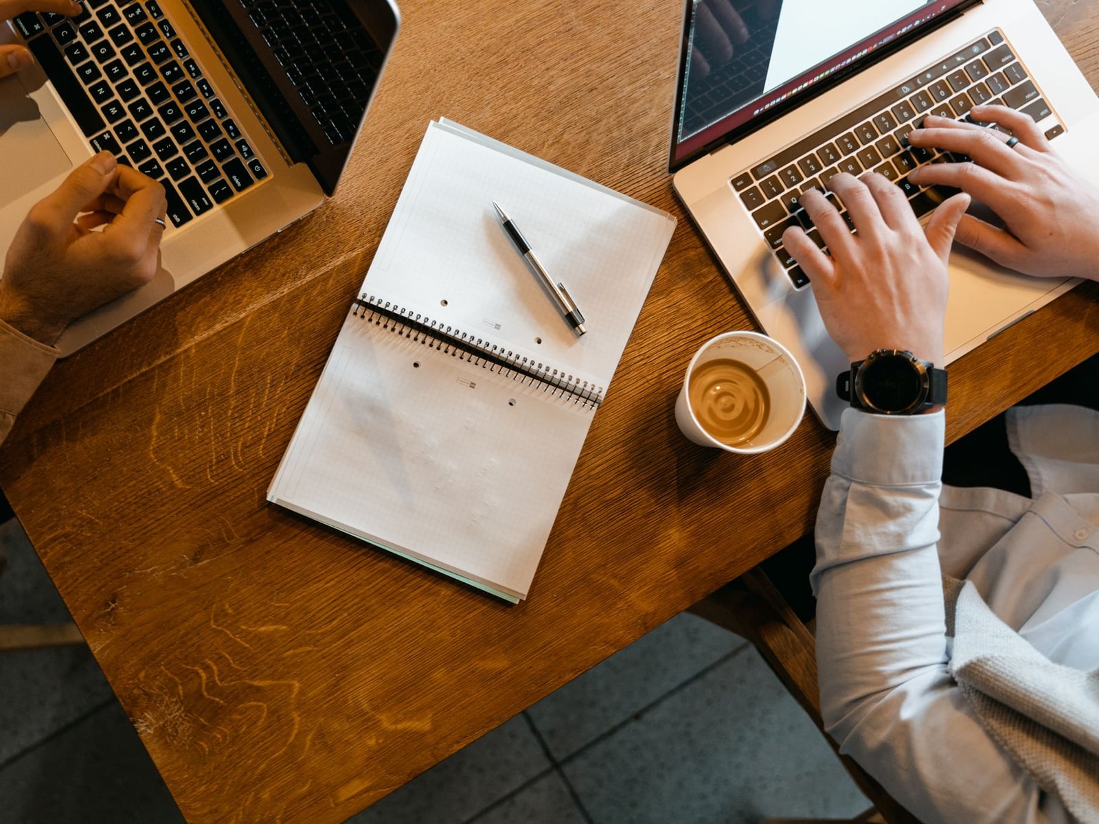 A laptop with a text editor open on a wooden desk in a Montreal cafe.
